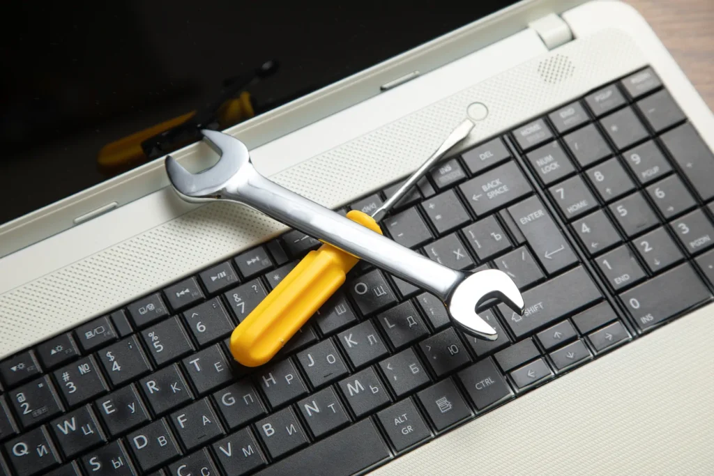 Llave inglesa y desarmador sobre teclado de laptop, representando mantenimiento técnico y seguridad informática.
