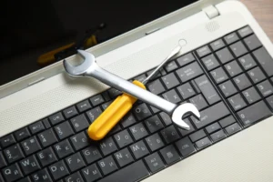 Llave inglesa y desarmador sobre teclado de laptop, representando mantenimiento técnico y seguridad informática.