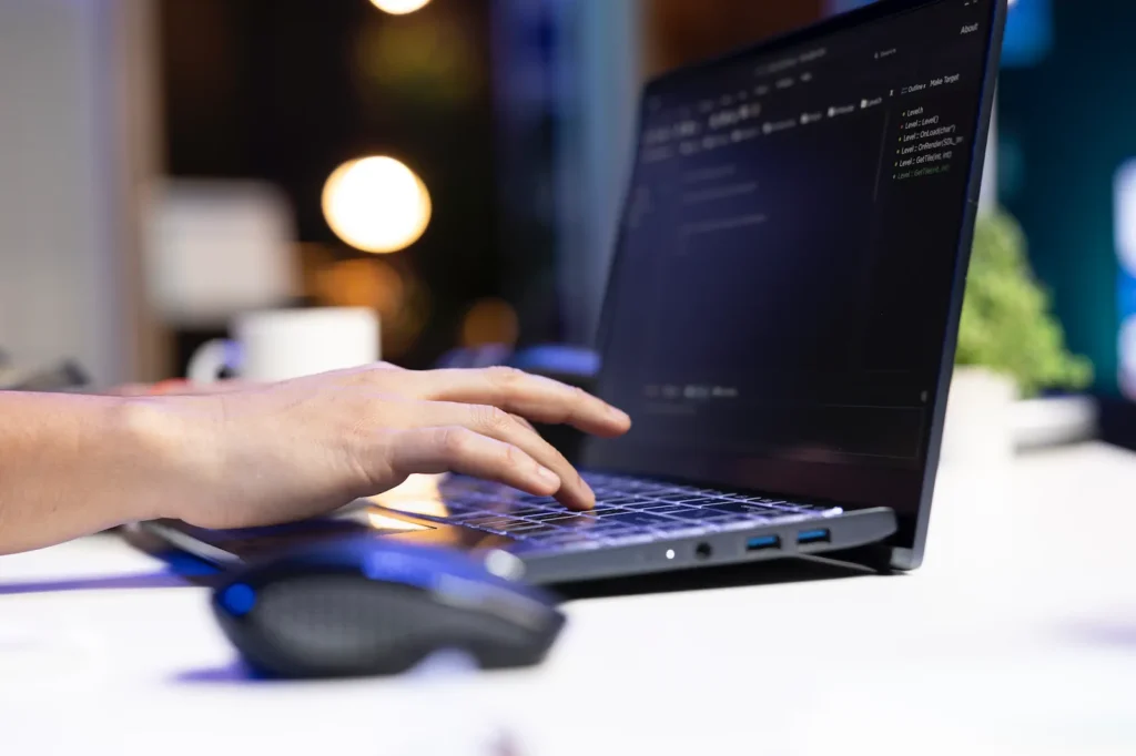 Person coding on a laptop with code on screen, representing monthly website maintenance.