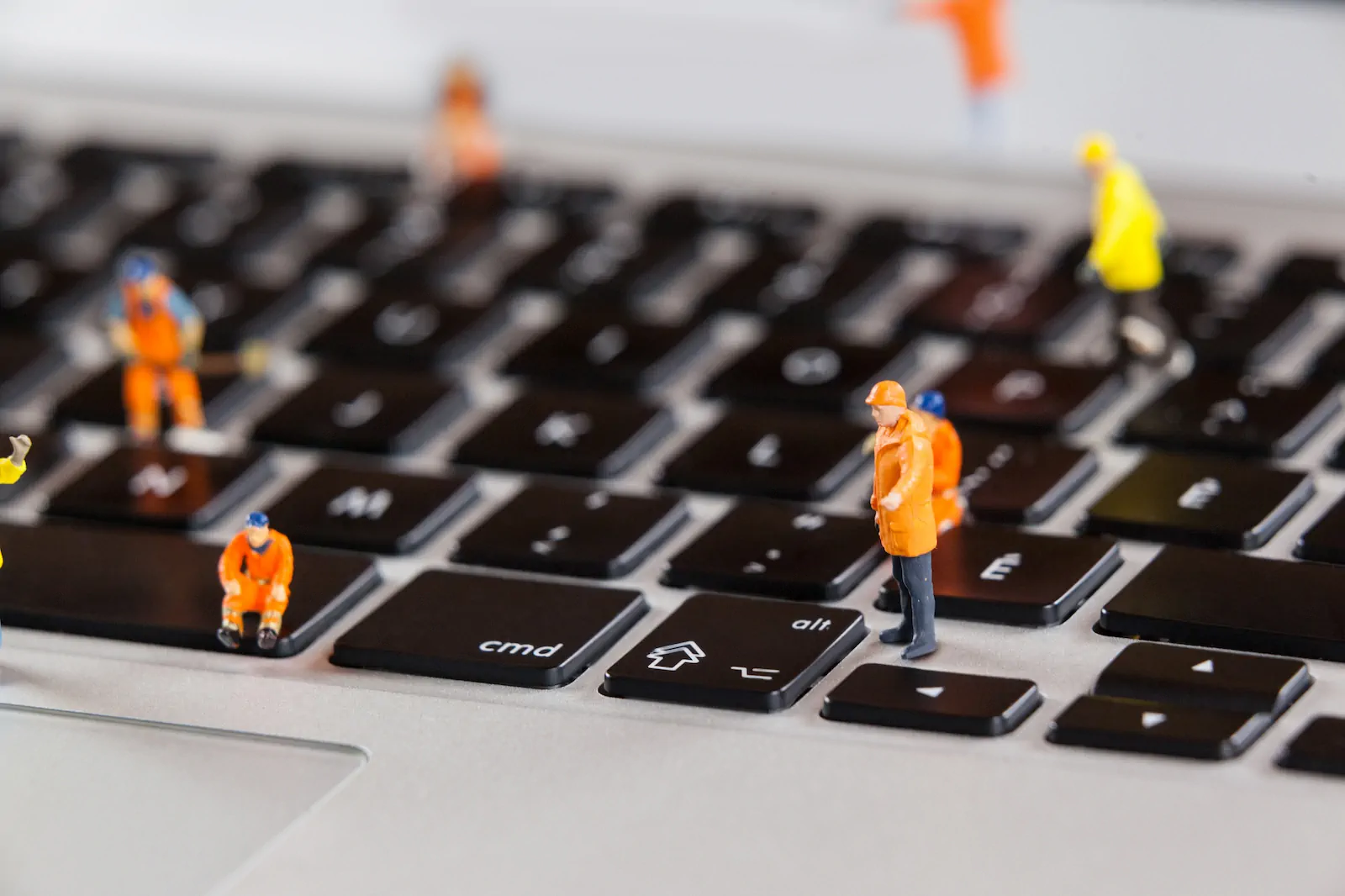 Keyboard with miniature worker figures symbolizing optimization and technical support.