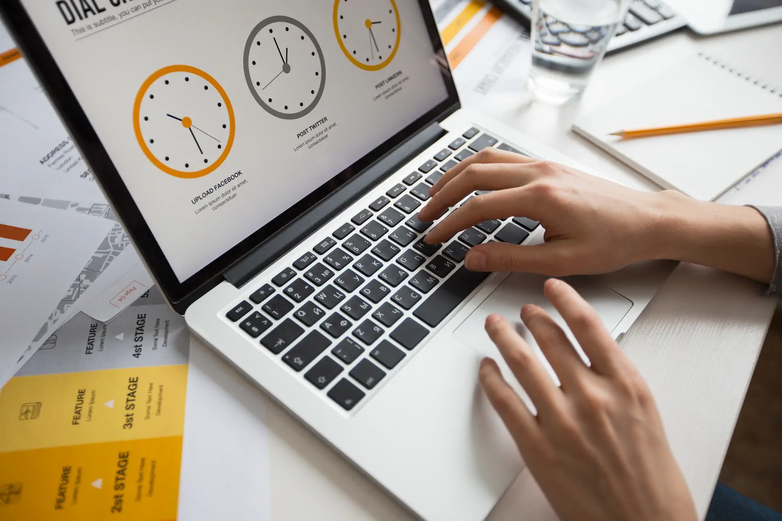 Hand typing on a laptop with performance charts and load-time clocks.