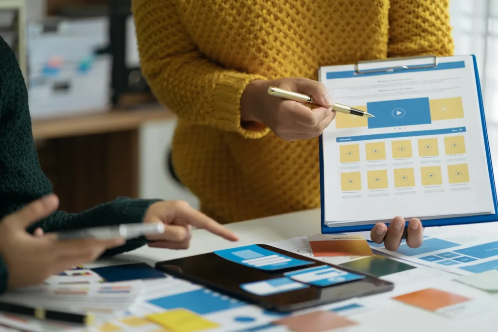 Person organizing website design structures on tablet and paper.