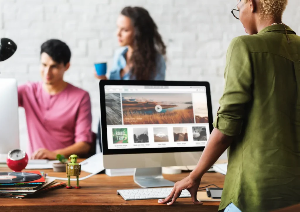 Team collaborating in front of a computer with web design on screen.
