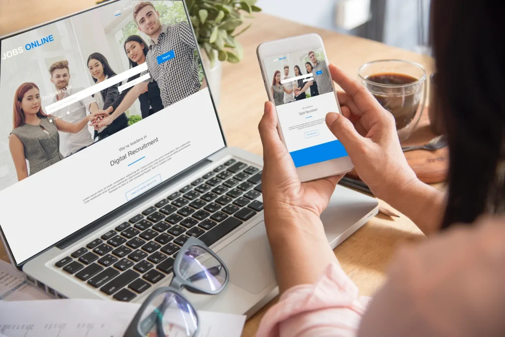 Person using a laptop and smartphone to manage an optimized website.