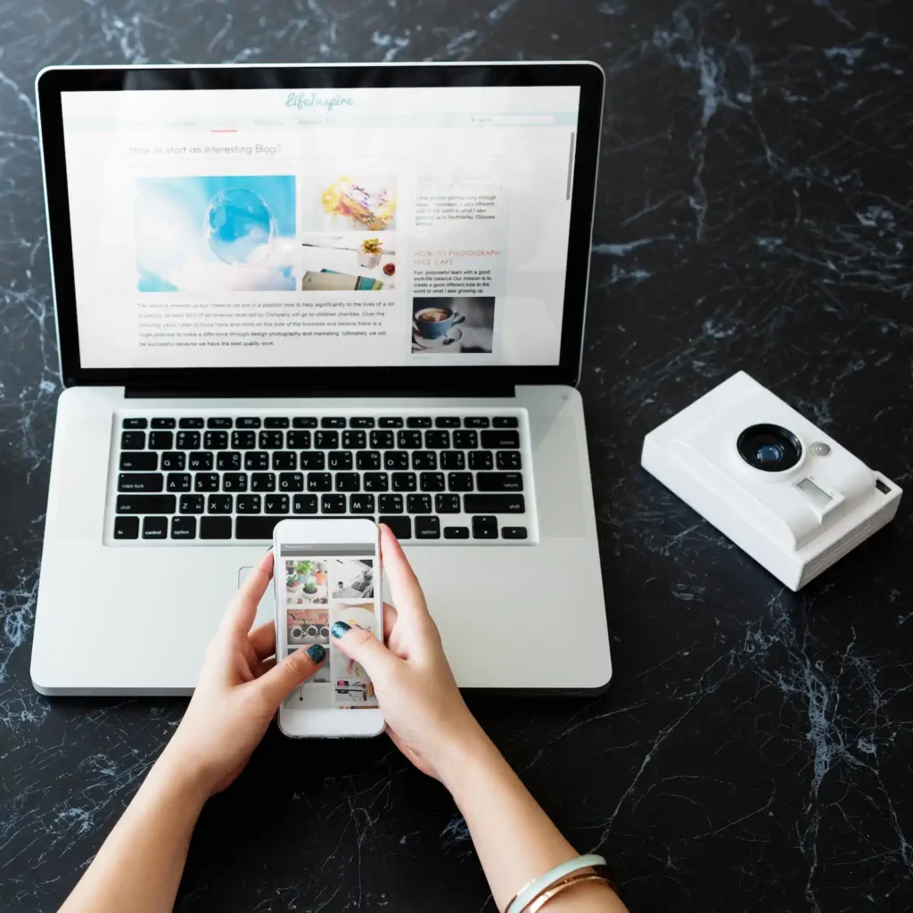 Usuario usando smartphone conectado a laptop para gestión de contenido digital