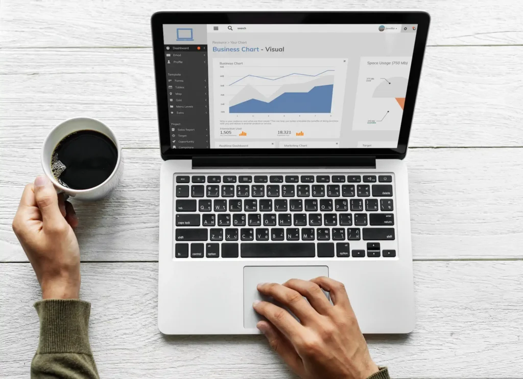 Laptop showing business charts next to a cup of coffee