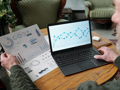 Persona analizando gráficos financieros en portátil y documento