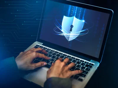 Manos tecleando junto a icono de ciberseguridad en portátil