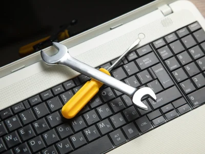 Llave inglesa y desarmador sobre teclado de laptop, representando mantenimiento técnico y seguridad informática.